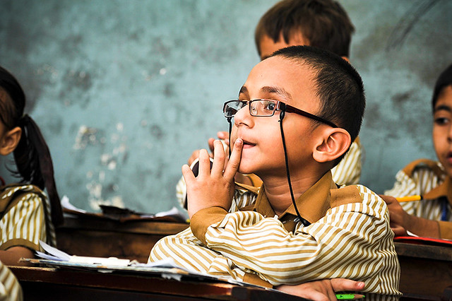 School boy sitting at a desk wearing spectacles