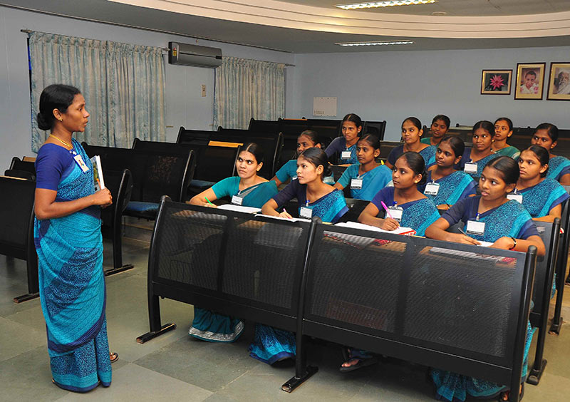 Female tutor standing in front of students in a small lecture room