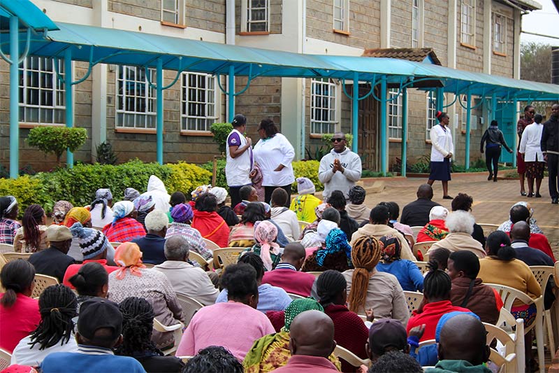 A large crowd of people sitting down outside the hospital building