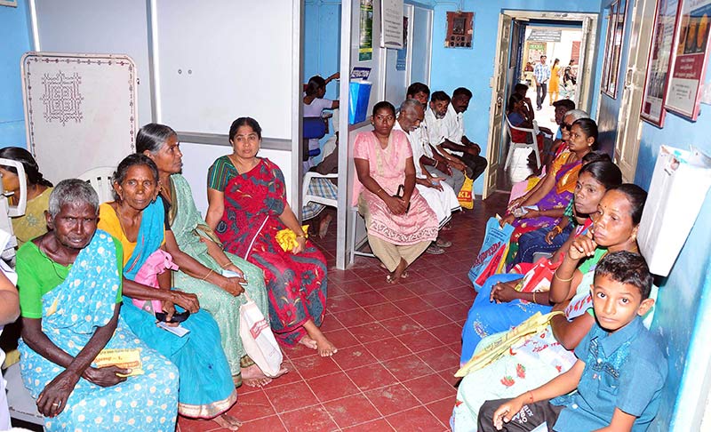 Several patients sitting either side of a waiting area and in a corridor outside a clinical room