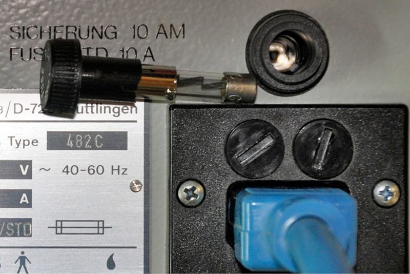 A fuse next to a plug, on top of a piece of equipment.