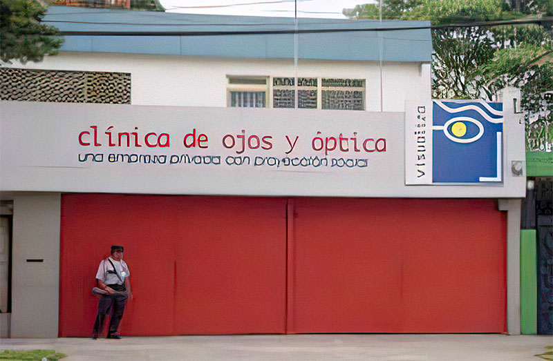 A person stands outside the building. There are large red doors in front of the clinic building.