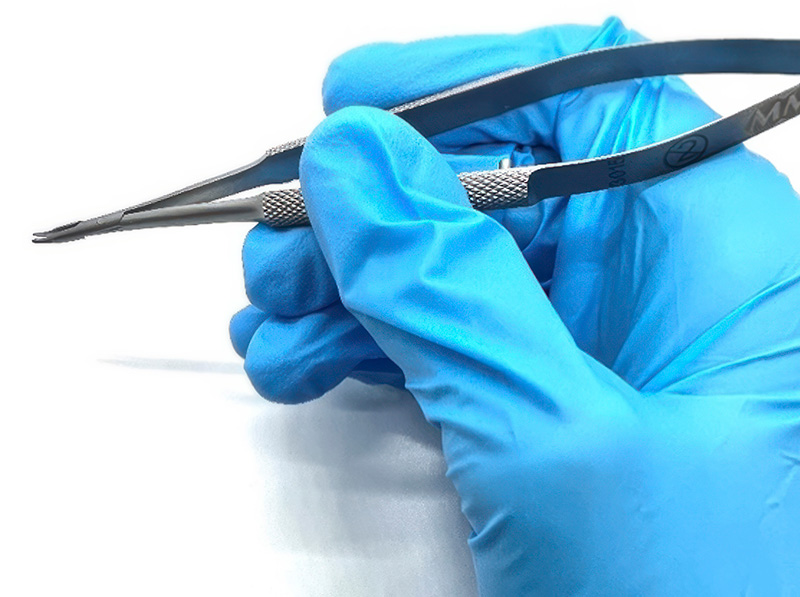 A gloved right hand holding metal forceps