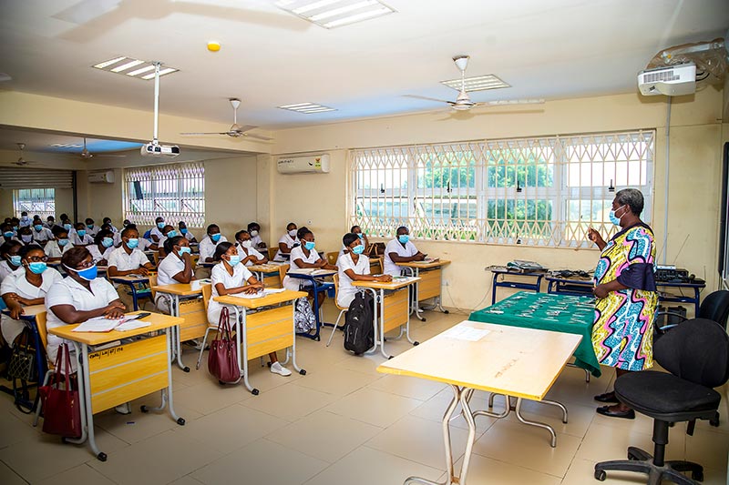Student nurses sitting in a classroom being taught by a qiulaified/senior nurse who is standing up in front of them