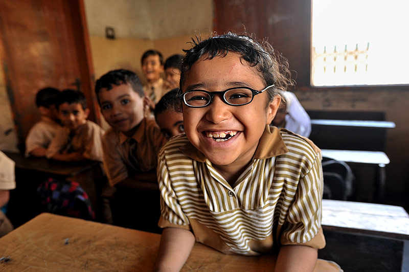 School child wearing glasses and smiling in the classroom
