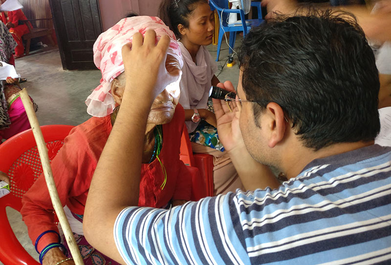 Male eye care staff member examines a lady's eyes using a torch