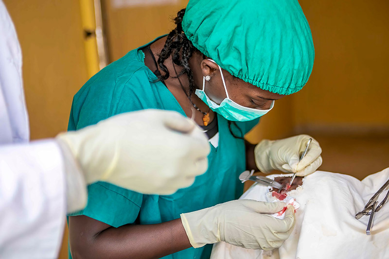 A trichiasis surgeon sits at the head of a patient on whom she is operating