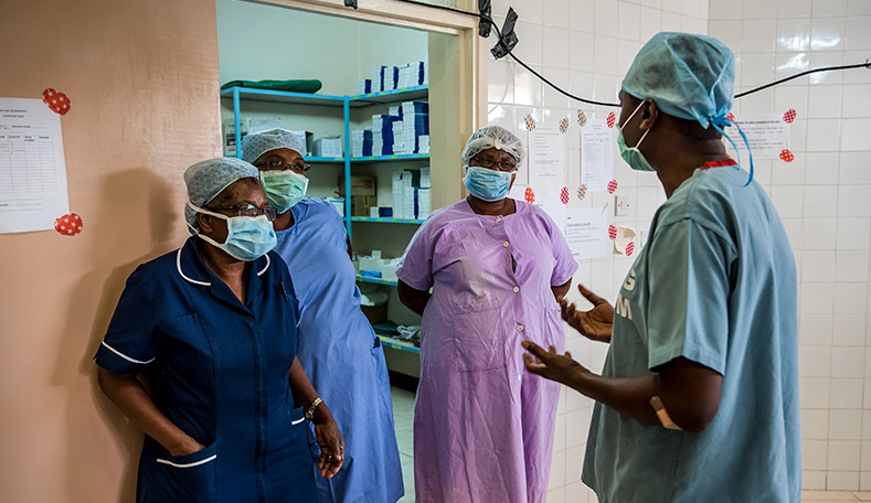 Surgeon discussing operation with 3 ophthalmic nurses outside an operating theatre