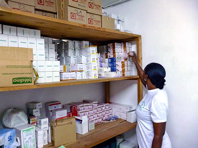 Female pharmacist reaching for stock from shelves