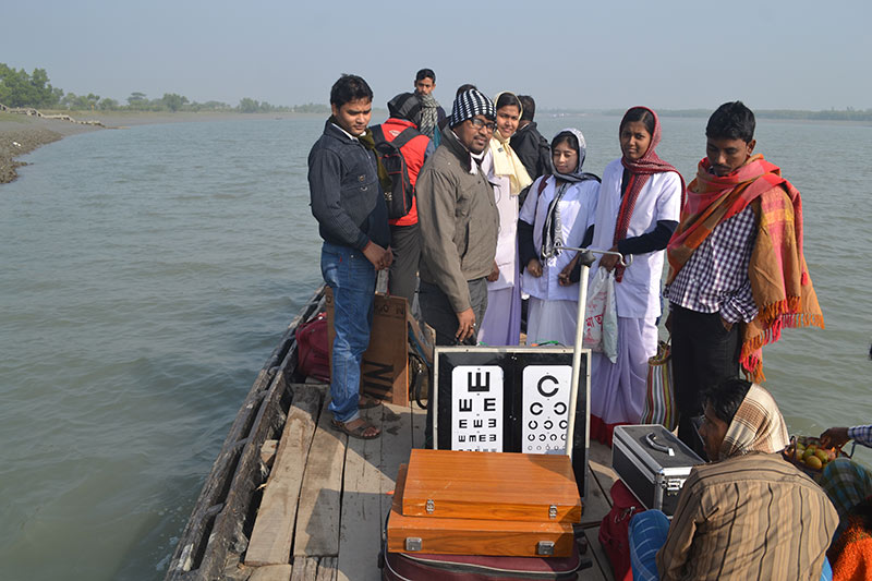 A group of people on a boat with vision charts and cases with optical refraction kits