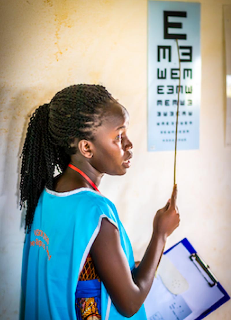 Female eye care worker pointing with a stick to a tumbling E chart