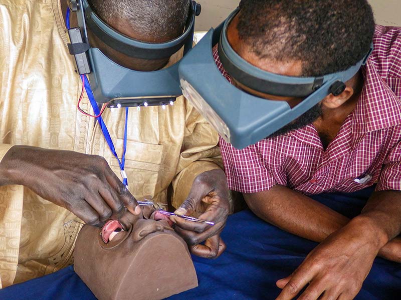 Two male eye health workers practice their surgical skills on a mannequin head
