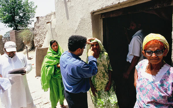 Examining eyes door to door in a village. PAKISTAN. © Jamshyd Masud/Sightsavers.