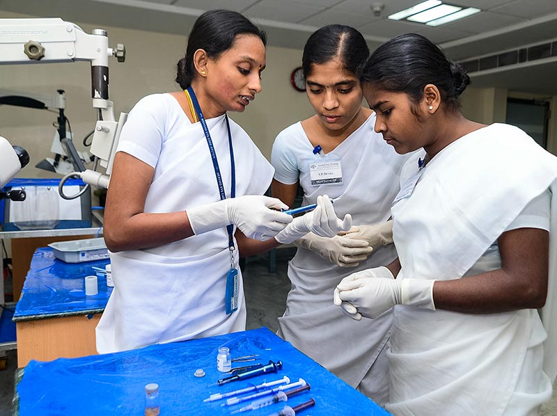Female nurse supervisor showing two student nurses an item of equipment in the operating theatre